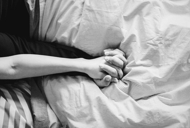 Couple holding hands in bed