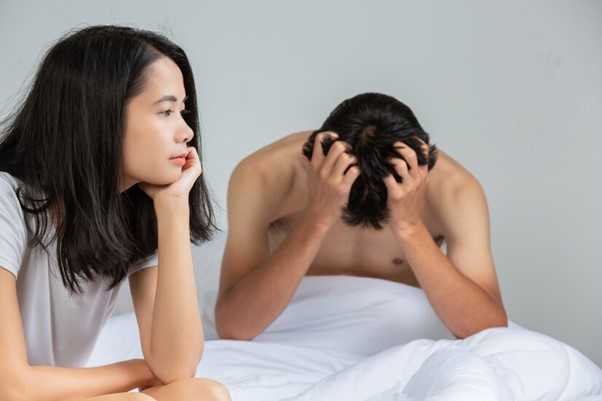 Couple laying in bed frustrated